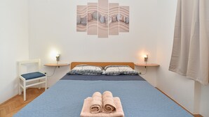 A bedroom with a bed, two bedside tables, a chair, and a wall art piece. - Apartment 108/217 (Istria - Valbandon), 700m from the beach (Valbandon)
