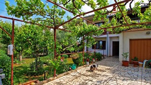A courtyard with a pergola, potted plants, and a dog. - Apartment 108/217 (Istria - Valbandon), 700m from the beach (Valbandon)
