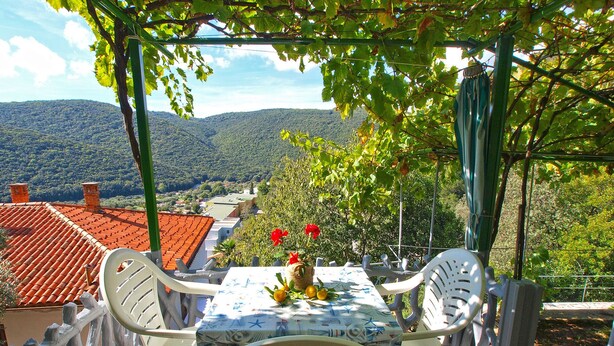 An outdoor dining area with a table and chairs, surrounded by a white fence, overlooking a mountainous landscape. - Apartment 154/328 (Istria - Rabac), 300m from the beach (Rabac)