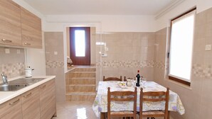 A kitchen with a dining area, wooden cabinets, a sink, and a table set for dining. - Apartment 154/328 (Istria - Rabac), 300m from the beach (Rabac)
