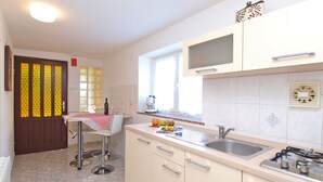 A kitchen with a sink, stove, and a window. There is a table with chairs and a bottle of wine. - Apartment 154/329 (Istria - Rabac), 300m from the beach (Rabac)