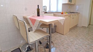 A kitchen with a dining table, chairs, a bottle of wine, and a window. - Apartment 154/329 (Istria - Rabac), 300m from the beach (Rabac)