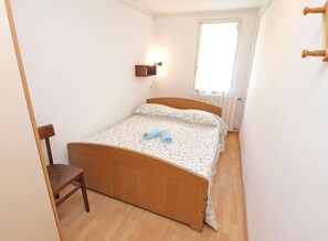 A small, neatly arranged bedroom with a wooden bed, a chair, a wall-mounted light, and a window with a view of the outside. - Apartment 154/329 (Istria - Rabac), 300m from the beach (Rabac)