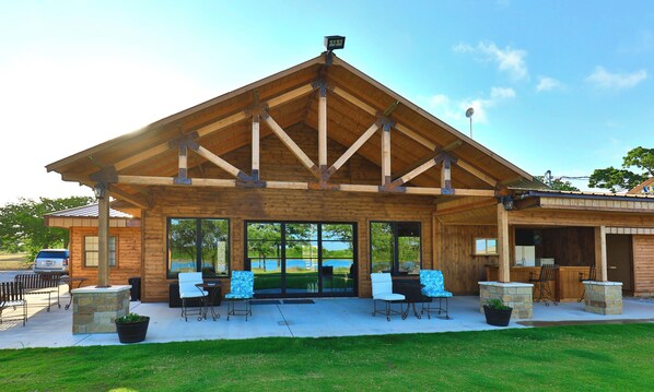 Un bâtiment en bois doté d’un patio couvert, de grandes fenêtres et d’un espace extérieur aménagé pour s’asseoir.