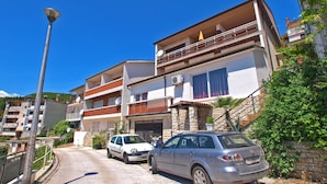 A residential building with multiple balconies, a car parked in front, and a street lamp. - Apartment 155/330 (Istria - Rabac), 500m from the beach (Rabac)