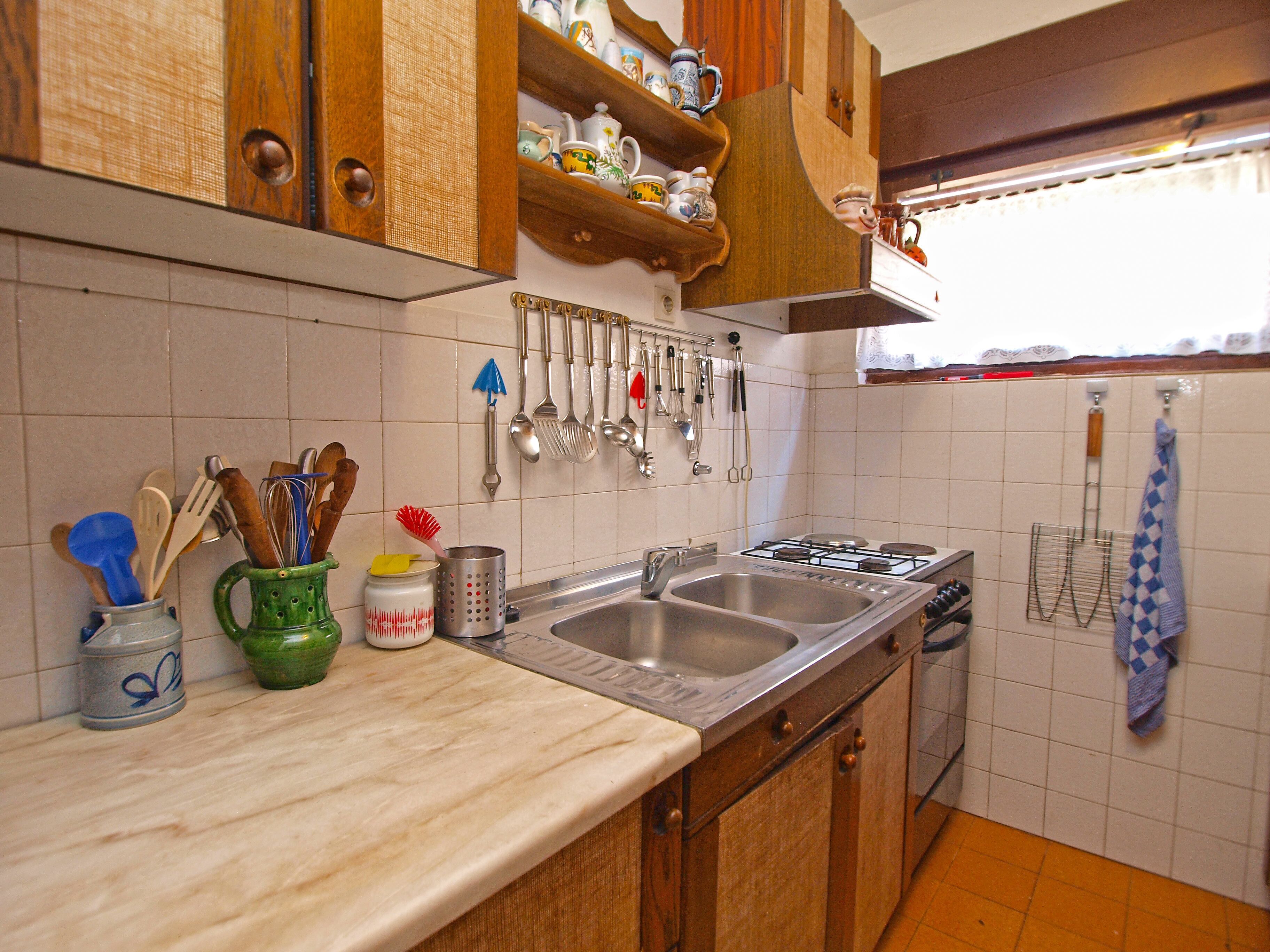 Eine Küche mit Holzausstattung, einer Spüle mit zwei Becken und diversen Küchenutensilien, die an der Wand hängen.