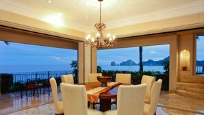 A spacious dining area with a large table and six chairs, overlooking a scenic view of the ocean and mountains. - Cabo La Estancia (Cabo San Lucas)