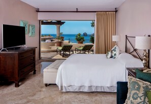A hotel room with a bed, a TV, a desk, and a balcony with a view of the ocean. - Cabo La Estancia (Cabo San Lucas)