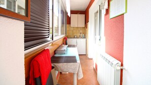 Un pasillo estrecho que conduce a una cocina con ventana, un radiador y una mesa con banco.
