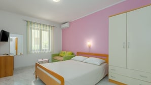 A bedroom with a bed, a wardrobe, a desk, a chair, and a television.