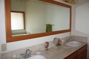 A bathroom with two sinks, a large mirror, and a window with blinds. - Jet Luxury at The Tara Del Sol Belize (San Pedro)