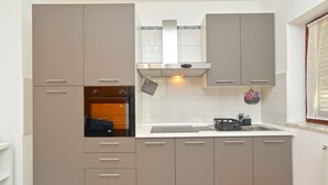 A compact kitchen with grey cabinets, a built-in oven, and a stainless steel sink. - Apartment 242/545 (Istria - Fažana), 200m from the beach (Fažana)