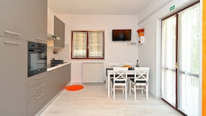 A modern kitchen with grey cabinets, a built-in oven, and a dining area with a white table and chairs. - Apartment 242/545 (Istria - Fažana), 200m from the beach (Fažana)