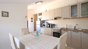 Una cocina compacta con mesa, sillas, microondas, cafetera y estufa.