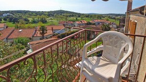 A balcony with a view of a residential area, a white plastic chair, and a striped awning. - Apartment 271/602 (Istria - Vrsar), 1000m from the beach (Vrsar)
