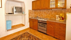 A kitchen with wooden cabinets, a stove, a sink, and a microwave. - Apartment 271/602 (Istria - Vrsar), 1000m from the beach (Vrsar)