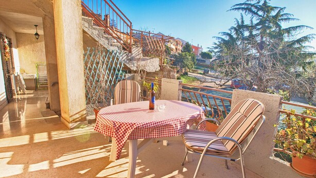 A balcony with a table and chairs, a view of a street and buildings, and a railing. - Apartment 279/619 (Istria - Vrsar), 100m from the beach (Vrsar)