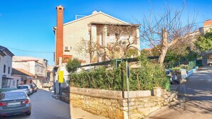 A narrow street with parked cars, a stone wall, and a building with a chimney. - Apartment 279/619 (Istria - Vrsar), 100m from the beach (Vrsar)