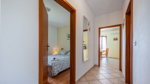 A hallway with a bed, a chair, and a dining area visible through an open door. - Apartment 294/648 (Istria - Labin), 800m from the beach (Labin)