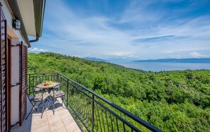 Un balcón con mesa y sillas, con vistas a un paisaje verde exuberante y una masa de agua.