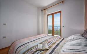 A bedroom with a bed, a window with a view, and a curtain.
