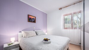 A bedroom with a bed, nightstand, and a window with curtains.