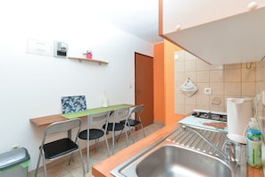A compact kitchen with a sink, stove, and chairs.