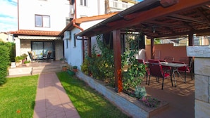 A patio area with outdoor furniture, a stone wall, and a pathway leading to a building with a tiled roof.