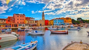 A harbor with colorful buildings and a prominent tower. Boats are docked along the water.