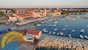 A marina with boats docked, a town in the background, and a building with a red roof in the foreground.