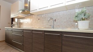 A modern kitchen with dark wood cabinets, a stainless steel range hood, and a tiled backsplash.