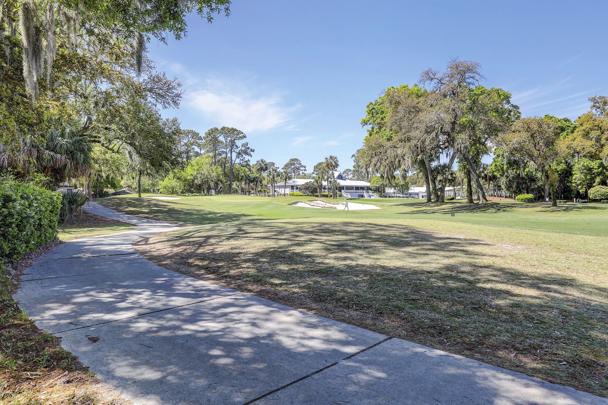 Un parcours de golf avec un chemin bien défini, des arbres et un bâtiment en arrière-plan.