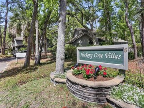 Naamplaatje voor Hickory Cove Villas, met een stenen plantenbak en rode bloemen ervoor.