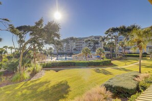 A resort with a swimming pool, palm trees, and a building with multiple balconies.