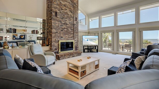 Un amplio salón con chimenea de ladrillo, ventanas grandes y vistas al exterior.