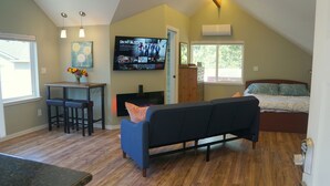 Un espacio habitable compacto con kitchenette, un sofá, comedor y cama.
