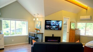 Una sala de estar con chimenea, un televisor montado en la pared y un ventanal grande.