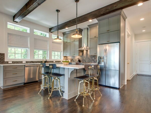A spacious kitchen with a central island, stainless steel appliances, and pendant lighting.
