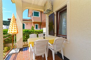 A balcony with a table and chairs, a checkered umbrella, and a window with shutters. - Apartment 336/769 (Istria - Poreč), 800m from the beach (Porec)