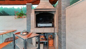 An outdoor brick oven with a table and chairs nearby.