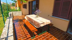 An outdoor patio with a table and benches, surrounded by a brick wall and a garden. - Apartment 349/808 (Istria - Peroj), 700m from the beach (Peroj)