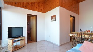 A living room with a television, a dining table with chairs, and a bed with a striped blanket. - Apartment 349/809 (Istria - Peroj), 700m from the beach (Peroj)