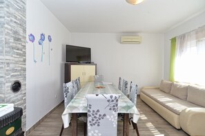A dining area with a table, chairs, a sofa, and a TV on a cabinet. - Apartment 351/776 (Istria - Fažana), 300m from the beach (Fažana)