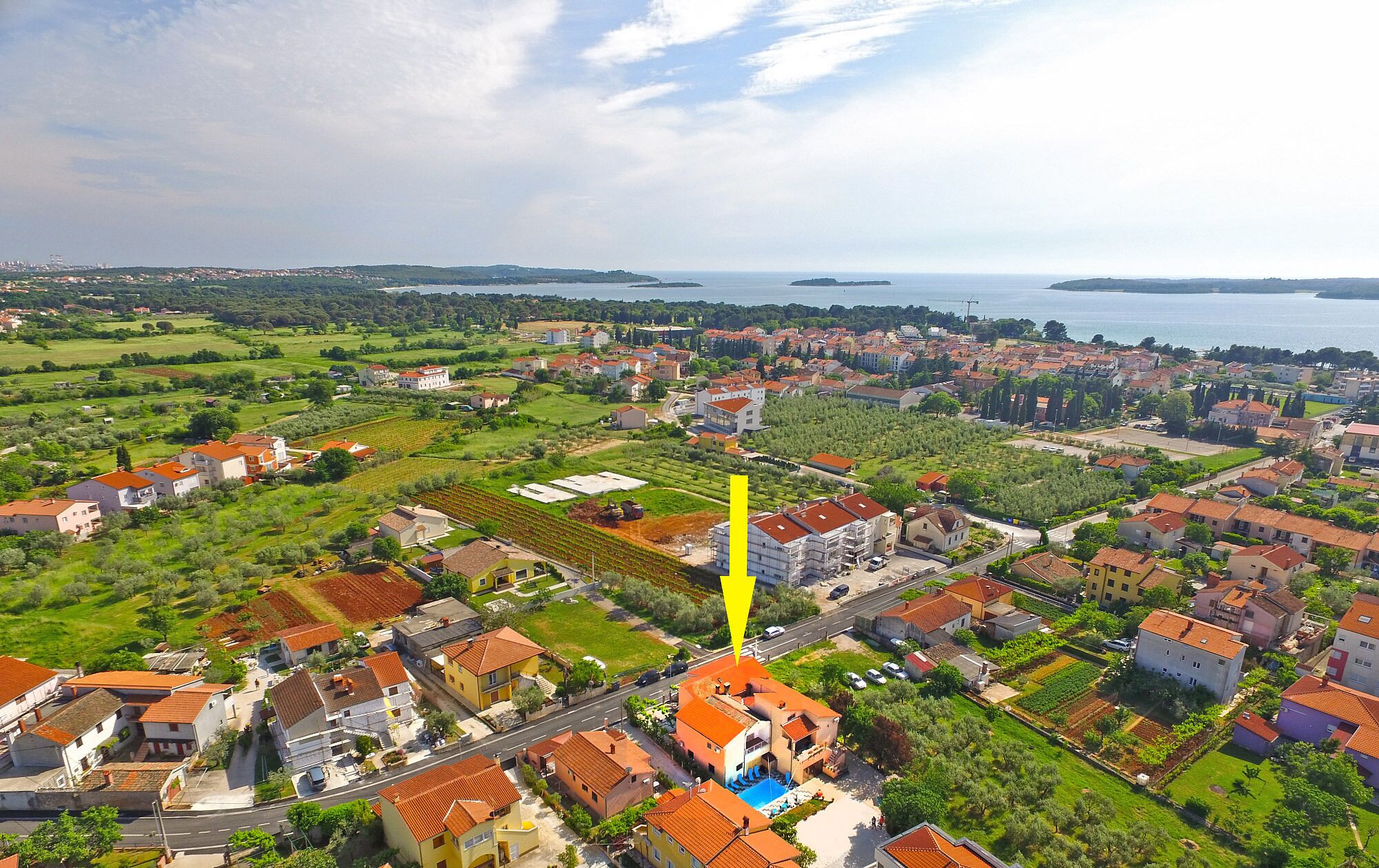 An aerial view of a coastal town with a mix of residential buildings and open green spaces.