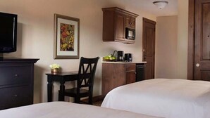 Une chambre d’hôtel avec deux lits, un bureau avec une chaise, un four à micro-ondes et une machine à café.
