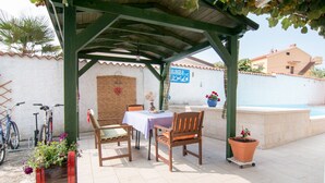 A covered patio with a table and chairs, a potted plant, and a bicycle. - Apartment 354/821 (Istria - Valbandon), 950m from the beach (Valbandon)