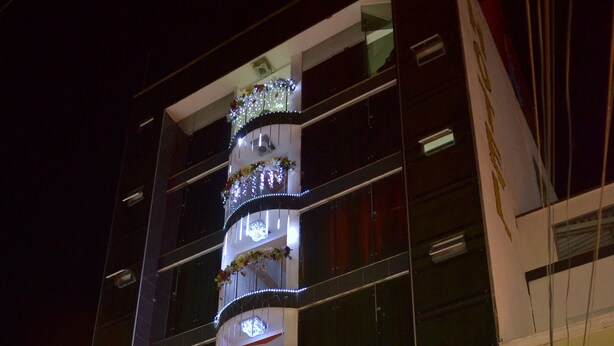 A multi-story hotel with balconies, illuminated by string lights and floral decorations. - Hotel Grand Latino Ibague (Ibagué)