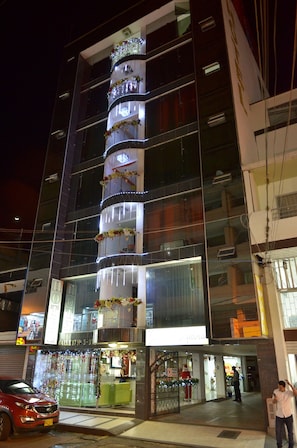 Un hotel de varios pisos con balcones, iluminado con luces de cadena y adornos florales.