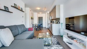A modern living room with a grey sofa, a coffee table, and a TV on a white stand.