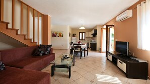 A living room with a sofa, coffee table, TV, and kitchen area with a dining table. - House 377/857 (Istria - Sveti Lovreč), 18000m from the beach (Sveti Lovreč)